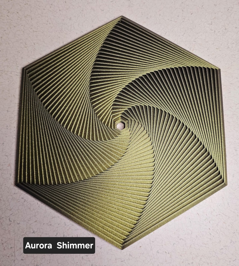 May include: A hexagonal, gold-colored, geometric wall art piece with a swirling pattern. The piece has a textured, shimmery finish.