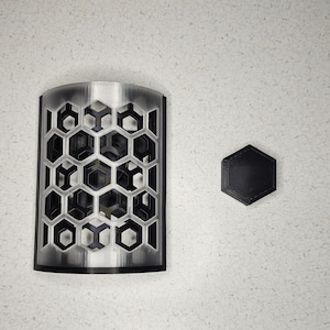 May include: A silver metal wall sconce with a honeycomb pattern and a black hexagonal base.