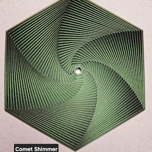 May include: A green hexagonal geometric design with a swirling pattern. The design has a metallic sheen and is called "Comet Shimmer".
