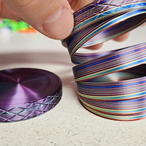 May include: Two circular, multi-colored, striped, coiled, decorative items. One is purple and the other is a stack of four, with colors of blue, green, red, and white.