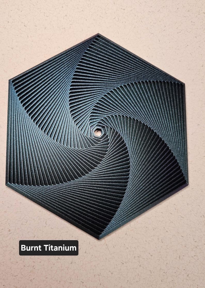 May include: A dark blue, hexagonal, geometric design with a swirling pattern. The design is made of thin lines that create a sense of depth and movement. The text "Burnt Titanium" is visible below the design.