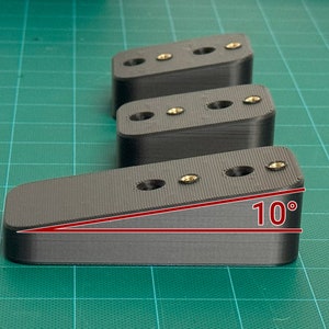 May include: Three black plastic blocks with screw holes. The block on the right is angled at 10 degrees.