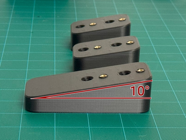 May include: Three black plastic blocks with screw holes. The block on the right is angled at 10 degrees.