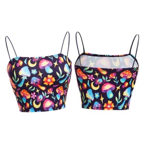 May include: A black crop top with thin straps, featuring a colorful pattern of mushrooms, flowers, moons, and stars. The design includes shades of blue, orange, yellow, and pink. The top is shown from the front and back.