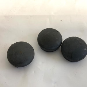 May include: Three black rubber caps, likely for furniture legs or other objects.