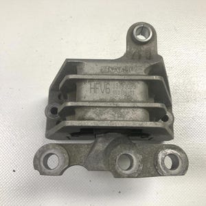 May include: A silver-colored metal automotive part with multiple mounting points and the text "SAAB" and "HFV6" visible. The part has a rectangular body with a cylindrical opening at the top and three circular openings at the bottom.