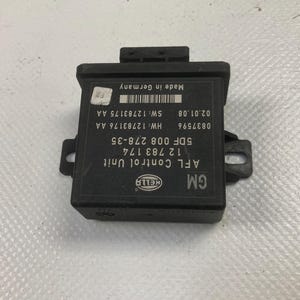 May include: Black AFL Control Unit with the HELLA logo and the GM logo. The unit has text that includes "Made in Germany" and various codes and numbers. The unit has a rectangular shape with a protruding top and two side brackets.