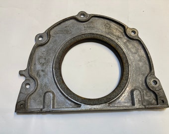 May include: A silver metal engine part with a round opening and a rubber gasket. The part has the text "Rotation" and "Genuine Parts" printed on it.