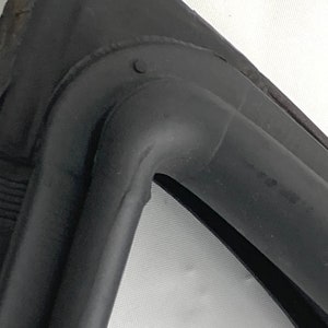 以下が含まれることがあります： 丸みを帯びた角を持つ黒いゴム製のシールをクローズアップ。シールは柔軟な素材でできており、表面はテクスチャ加工されています。