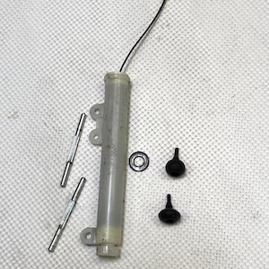 May include: A clear plastic tube with a black string attached to the top. There are three silver metal rods and two black rubber stoppers.