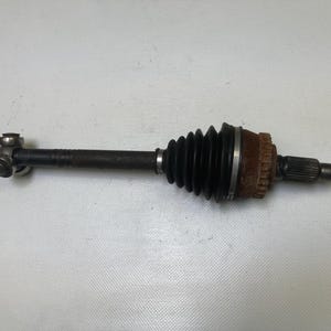 May include: A used automotive axle shaft, with a black rubber boot, a rusty brown end, and a metal joint. The shaft is dark with signs of wear, suggesting it is a used component.