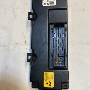 May include: A black electronic control module with a yellow warning label that reads "ATTENTION OBSERVE PRECAUTIONS FOR HANDLING ELECTROSTATIC DISCHARGE SENSITIVE DEVICES". The module has a label with the text "GM SAAB 12802127 AA HW 12796792 SW 12002128 AA 05 0219 80 HW: 09 SW: 45 00029296 42/04".