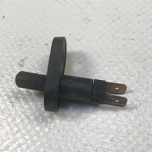 May include: A black automotive door jamb switch with two copper-colored terminals. The switch has a cylindrical body with a circular mounting ring and a protruding actuator.