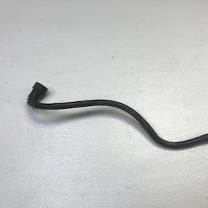 Op de afbeelding: Een zwarte, gebogen slang met een connector aan één uiteinde. De slang is gemaakt van een flexibel materiaal en lijkt te worden gebruikt in een automotive of mechanische toepassing. De achtergrond is een wit, getextureerd oppervlak.