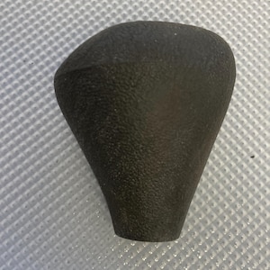 May include: A black rubber gear shift knob with a textured surface.