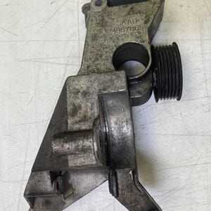 May include: A used metal car part, likely an engine component. The part is silver with some dark areas and a black pulley. The word "SAAB" and the number "4967865" are visible on the part.