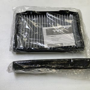 May include: Two new cabin air filters in plastic packaging. The top filter is rectangular with a black frame and gray filter material. A label with text is visible. A second, smaller filter is below.