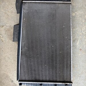May include: A silver radiator with black plastic end caps. The radiator has a rectangular shape and is made of metal.