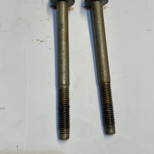 May include: Two silver metal bolts with hexagonal heads and a threaded shaft. The bolts are slightly rusted.