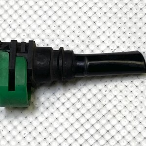 Op de afbeelding: Een zwarte en groene brandstofleidingconnector met een zwart kunststof behuizing en een groene kunststof clip. De connector heeft een zwarte rubberen slang.