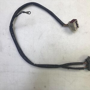 May include: A black electrical wire with two black connectors and one white connector with red accents.