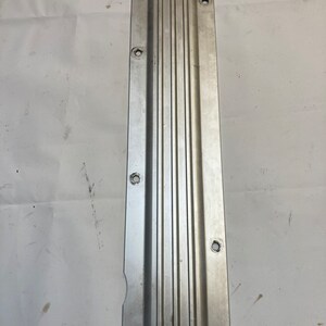 Puede incluir: Una tapa de válvula de metal plateado con un diseño acanalado y varios agujeros.