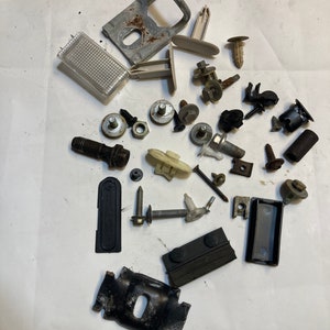 May include: Assortment of black, white, and gray plastic and metal car parts, including screws, clips, and brackets.