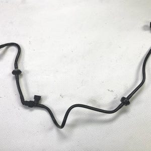 May include: A black automotive fuel line assembly with multiple bends and connectors. The flexible hose has a series of curves and is designed to transport fuel within a vehicle's engine system. The connectors are located at each end of the hose.