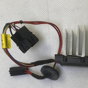 Puede incluir: Un componente eléctrico negro con un disipador de calor plateado y varios cables conectados a él. Los cables son rojo, negro, azul, verde y amarillo. El componente tiene un conector negro con una etiqueta amarilla que dice "SELCO".