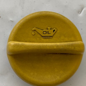 May include: Yellow oil cap with a black oil can symbol and the word "OIL" printed on it.