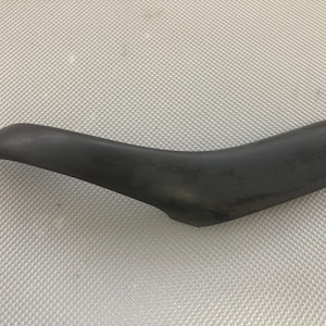 Op de afbeelding: Zwarte kunststof autodeurgreep met een gebogen ontwerp.