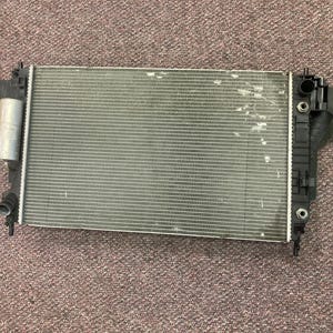 May include: A silver car radiator with black plastic components. The radiator is rectangular and made of metal with a grid pattern.