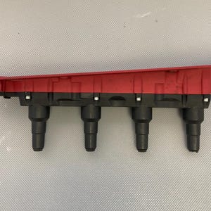 May include: Red and black automotive ignition coil pack with four spark plug wires.