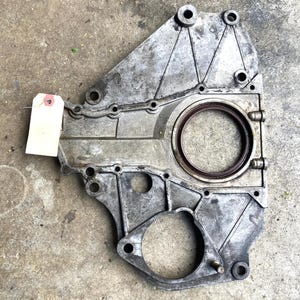 May include: A used, silver-colored metal engine part with multiple bolt holes and a circular seal. A blank tag is attached to the part. The part has a worn appearance, suggesting it is a used component.