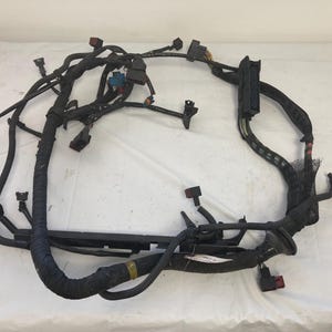 Peut inclure: Un faisceau de câblage automobile noir avec plusieurs connecteurs et fils. Le faisceau est enroulé et semble être utilisé pour un moteur de voiture.