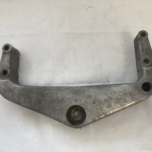 May include: A silver metal bracket with multiple holes and a rounded center section.