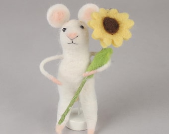 May include: A white felt mouse holding a yellow felt sunflower with a brown center. The mouse is standing on a white base.
