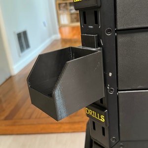 Puede incluir: Un sistema de almacenamiento de herramientas de metal negro con una bandeja de pl&aacute;stico negro etiquetada como "DRILLS". El sistema tiene una etiqueta que dice "ELECTRICAL" y otra etiqueta que dice "TOUGH STACK".