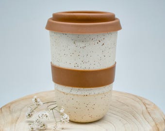 Tazza da viaggio in ceramica bianca fatta a mano con coperchio e rivestimento in silicone.