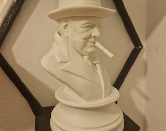 May include: A white 3D printed bust of a man wearing a hat and holding a cigar. The bust is on a white pedestal.