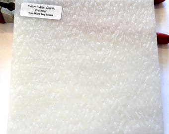 Puede incluir: Un azulejo cuadrado blanco texturizado con una etiqueta que dice "Wispy White Granite Wismach From Mixed Bag Mosaics".