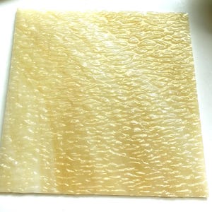 May include: A sheet of translucent, yellow-toned, textured acrylic. The texture resembles ripples or waves.