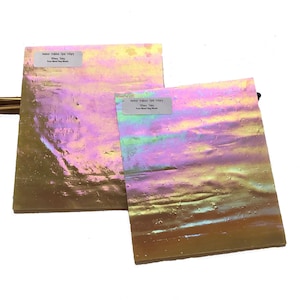 Può includere: Due fogli di vetro iridescente con un effetto arcobaleno. Il vetro è etichettato "Amber Irid Opal Vitry" e "Starry Sky".
