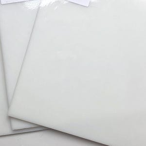 May include: Three white ceramic tiles stacked on top of each other. The tiles are smooth and glossy.