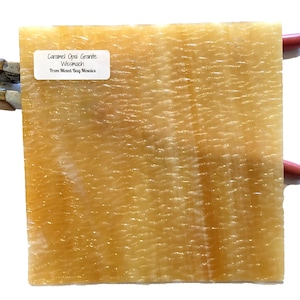 May include: A close-up of a caramel opal granite tile with a rippled texture. The tile is labeled "Caramel Opal Granite Wismach From Mixed Bay Mosaics".
