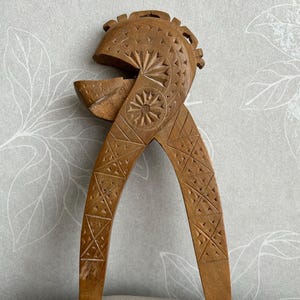 Peut inclure: Un casse-noisette en bois avec des sculptures complexes. Le casse-noisette a la forme d'une tête avec une grande bouche et un motif détaillé sur le devant.