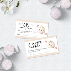 May include: Two baby shower raffle tickets with the text "DIAPER raffle". Each ticket features a smiling dumpling illustration and heart accents. The tickets read "Bring a pack of diapers of any size for a chance to win a prize!"