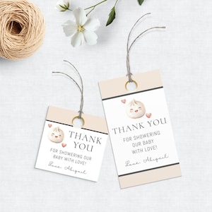 May include: Two pink and white thank you tags with a cartoon dumpling illustration. The text reads "Thank You for showering our baby with love! Love, Abigail".