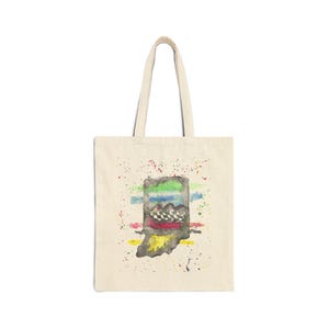 Peut inclure: Un sac fourre-tout en toile beige avec une illustration centrale à l'aquarelle de l'État de l'Indiana. Le motif comprend des bandes horizontales vertes, bleues, rouges et jaunes, un motif à damier noir et blanc et des éclaboussures de peinture.