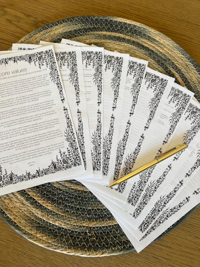 Peut inclure: Une pile de feuilles de papier blanc avec du texte imprim&eacute; en noir intitul&eacute; core values et des bordures florales complexes, accompagn&eacute;e d'un stylo &agrave; bille dor&eacute;. Les pages pr&eacute;sentent des sections lign&eacute;es pour &eacute;crire et des illustrations botaniques.